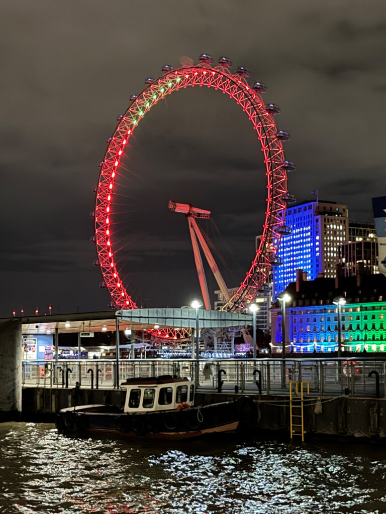 夜のテムズ川沿いに浮かぶライトアップされたロンドン・アイの観覧車