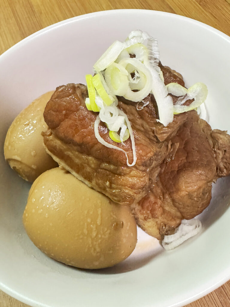 シェフドラムで作った豚の角煮の完成品。白いお皿にほろほろの豚バラ肉とゆで卵を盛り付け白ねぎを添えている