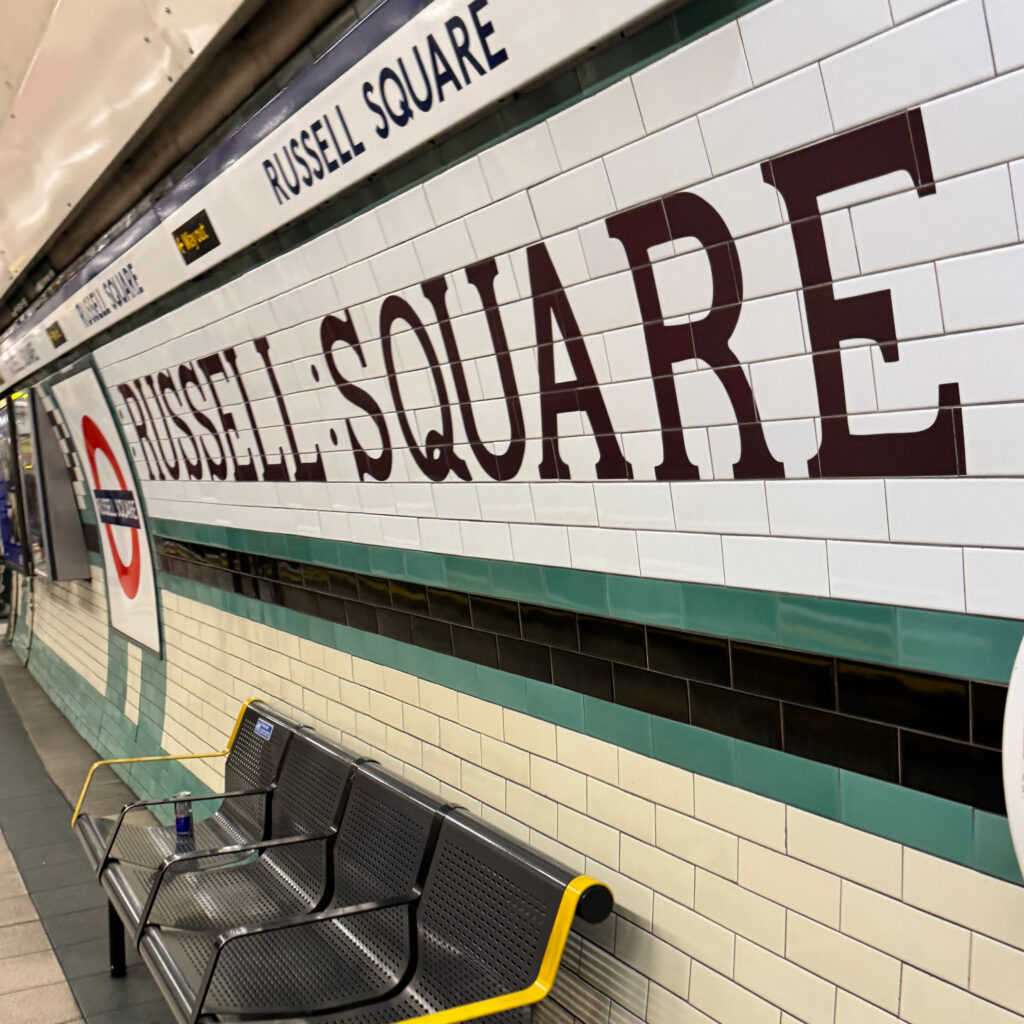 ラッセル・スクエア駅のプラットフォームにあるロンドン地下鉄のロゴが入った壁面の写真