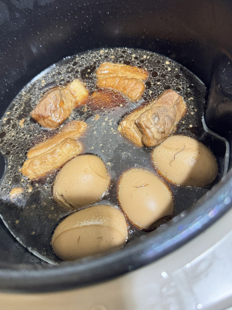 シェフドラムの内なべで豚バラ肉とゆで卵が醤油色の煮汁の中で煮えている様子