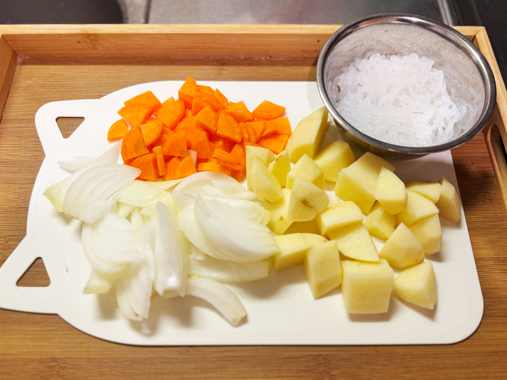 シェフドラムで肉じゃがを作るための材料。玉ねぎ・にんじん・じゃがいも・春雨をカットしてまな板に並べた状態